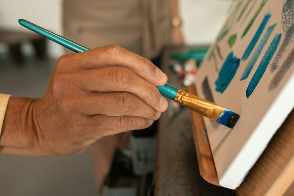 Close-up of artist's hand painting vibrant colors on canvas in studio.